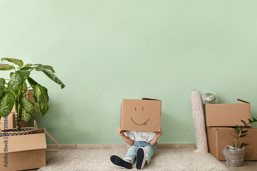 Kid with moving box having fun in new flat