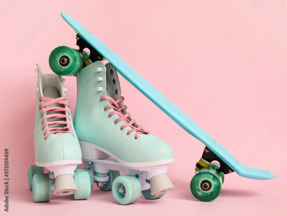 Roller skates with skateboard on color background