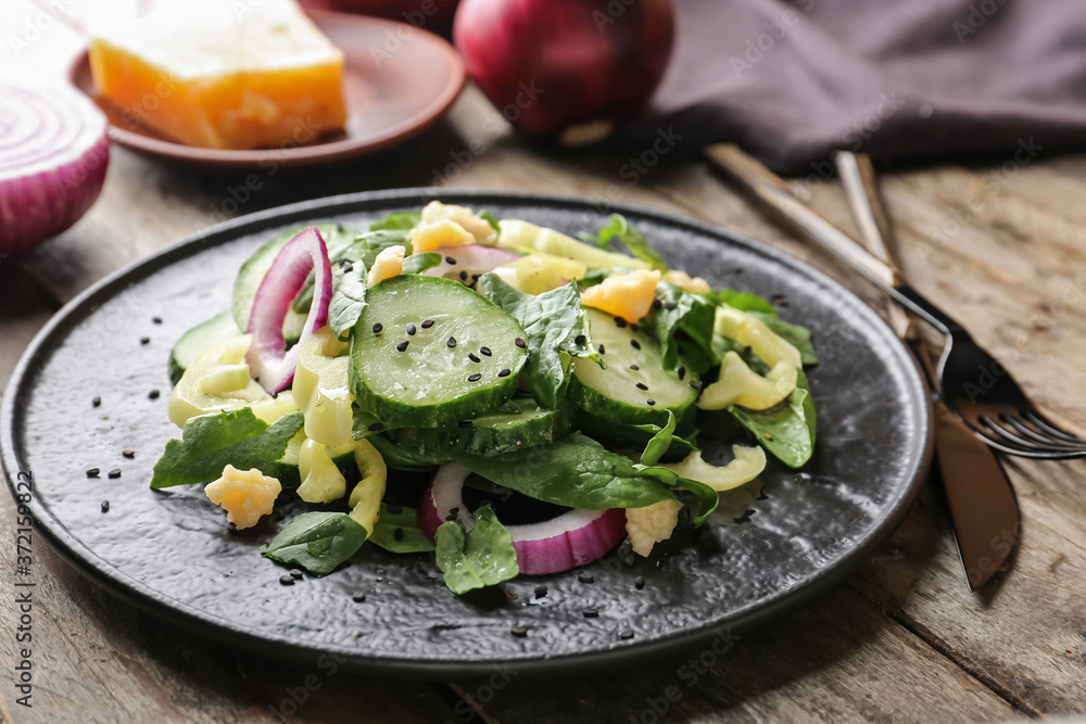 Plate with tasty cucumber salad on table