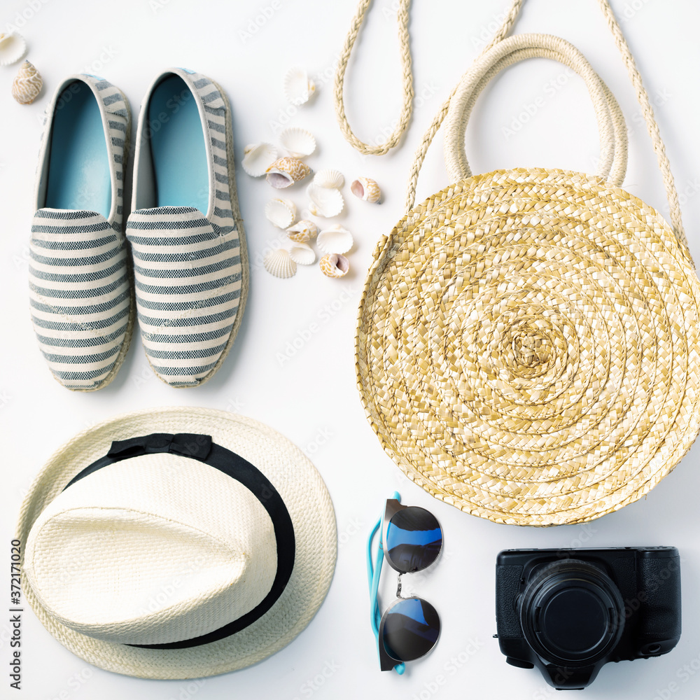 Flat lay traveler accessories on white background with straw hat, summer shoes, camera, bag and sung