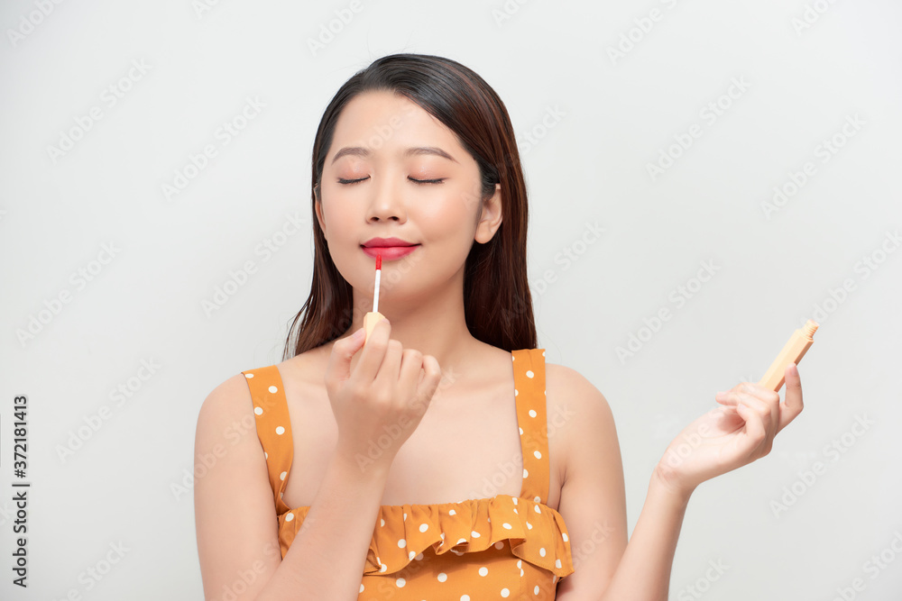 Cute girl applying lip gloss. Expressive facial expressions .Cosmetology