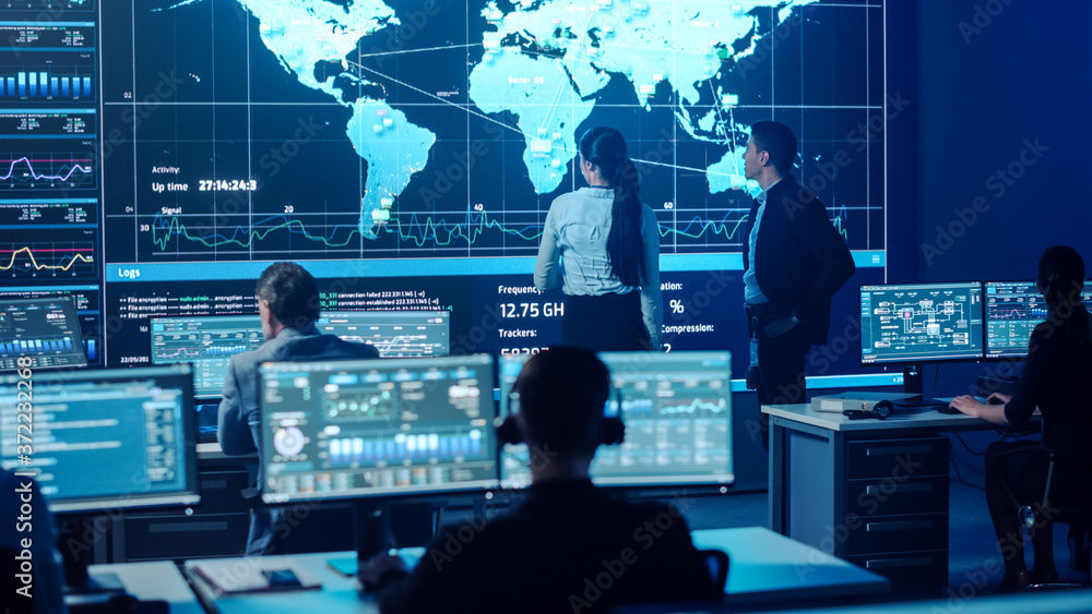 Project Manager and Computer Science Engineer Talking while Using Big Screen Display Showing Global 