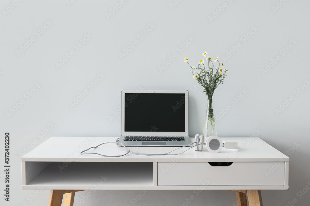 Workplace with laptop near light wall