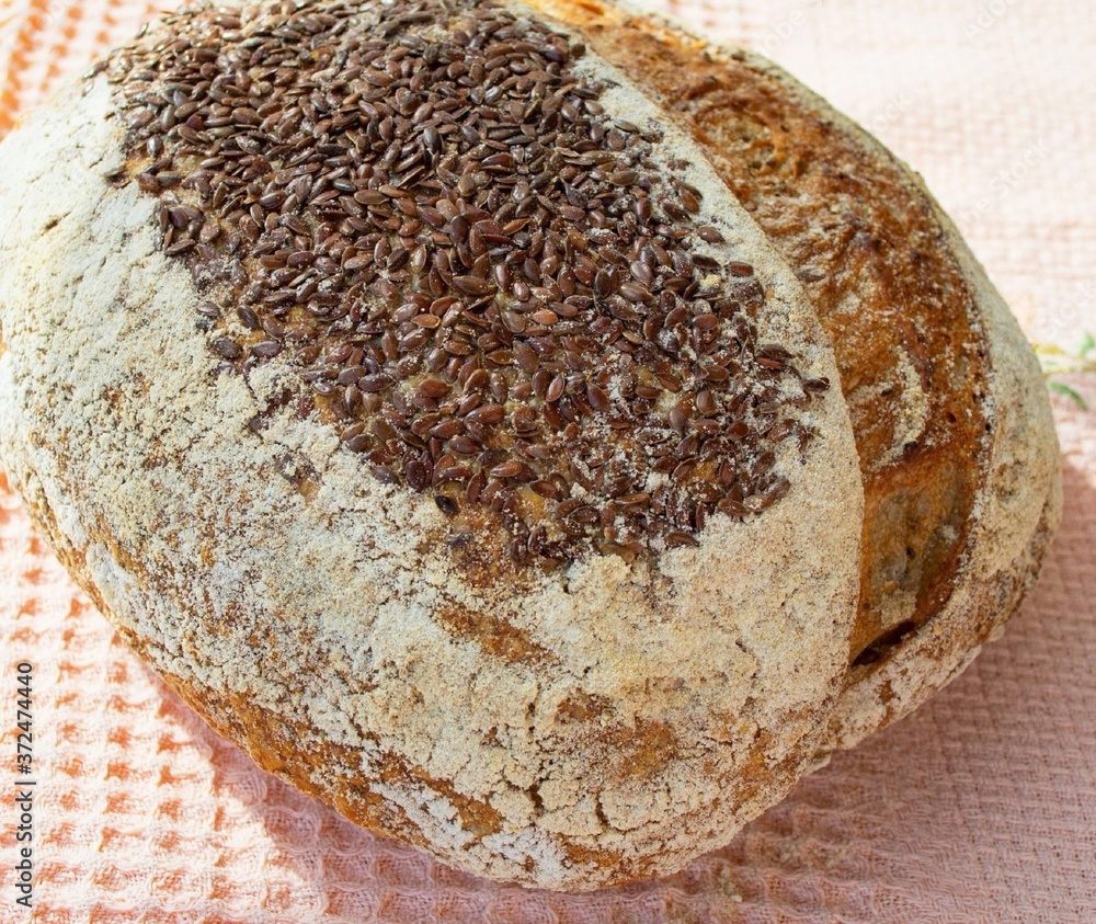 Whole grain homemade bread (French loaf) with flax seeds, in the rays of the bright sun. On a pink k