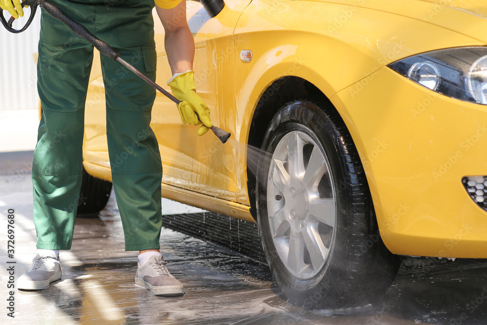 Worker of car wash cleaning modern automobile