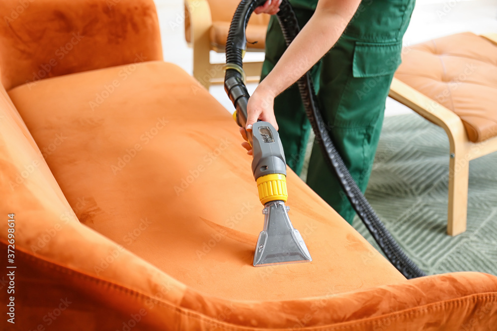 Dry cleaners employee removing dirt from sofa in house