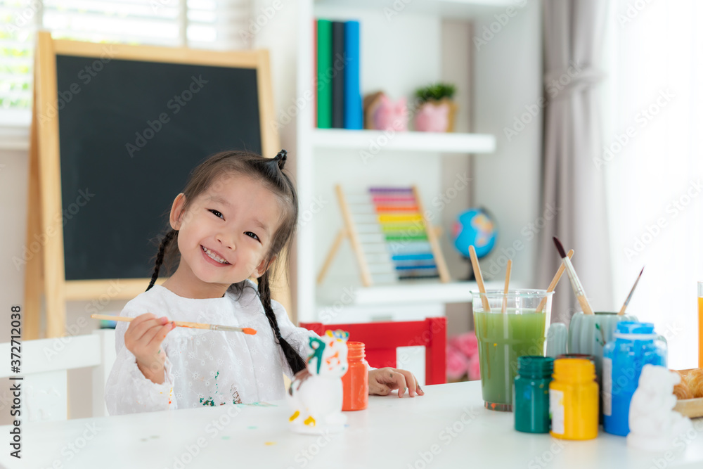 Asian kindergarten school girl painting Plaster doll with Acrylic water color paint and smiling look