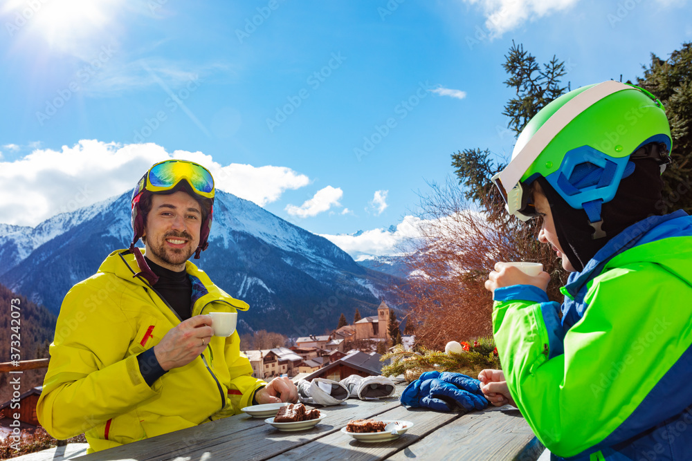 快乐微笑的家庭-穿着滑雪服的父亲和小男孩在山景船尾享受午休