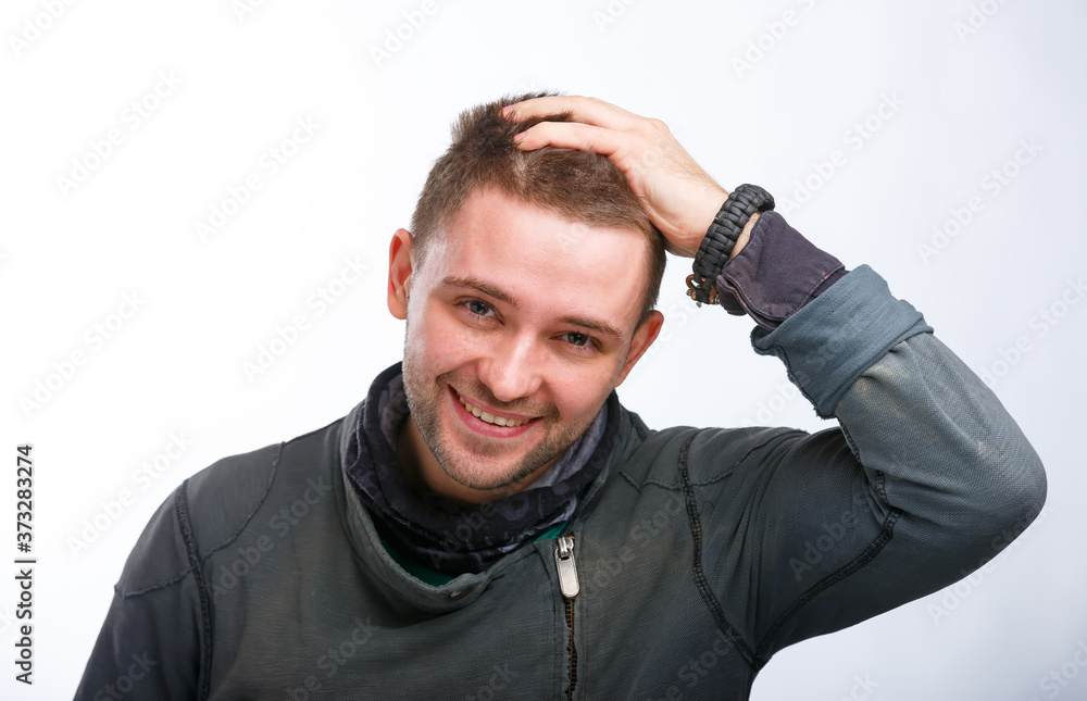 Portrait of the young happy smiling man isolated on a white background. Keeping hand on head.