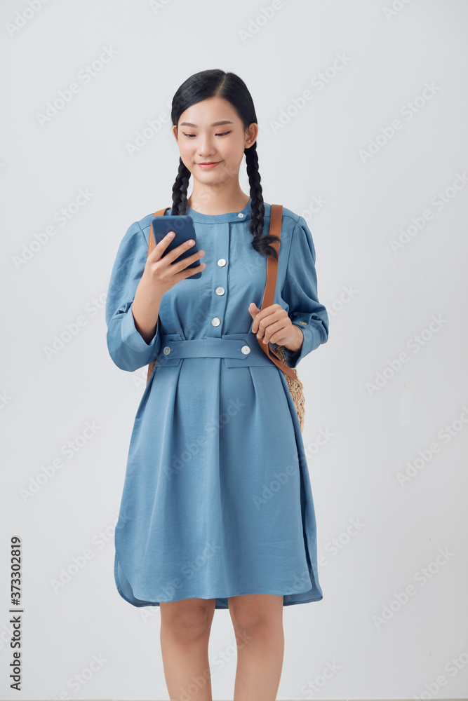 Nice charming attractive school girl holding in hands cellphone making smm post isolated over white 