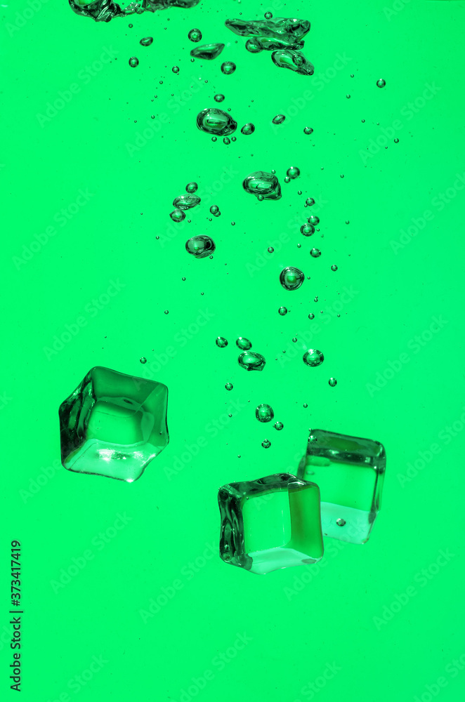 Falling of ice cubes into water on color background