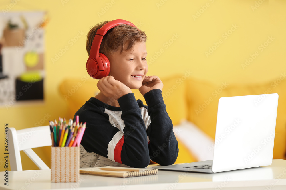 Little boy with headphones using laptop at home