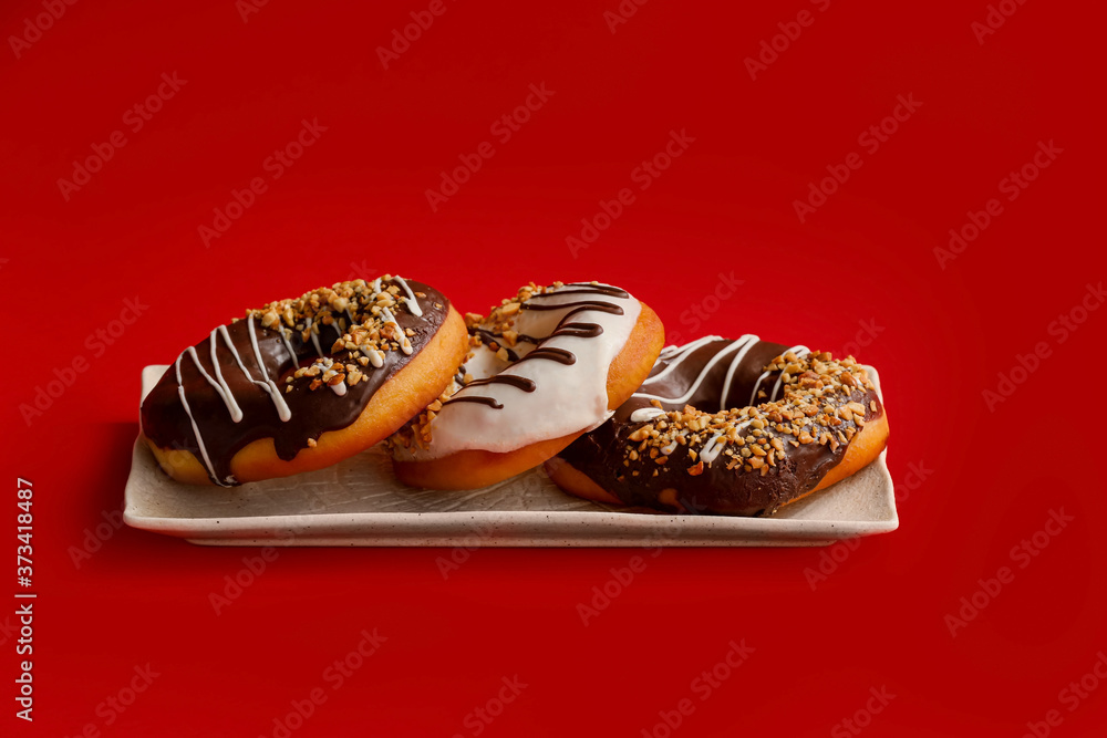 Plate with tasty donuts on color background