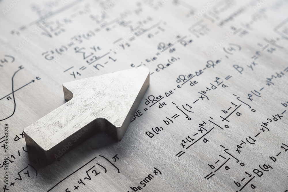 Chrome metal arrow on concrete wall with mathematical formulas.