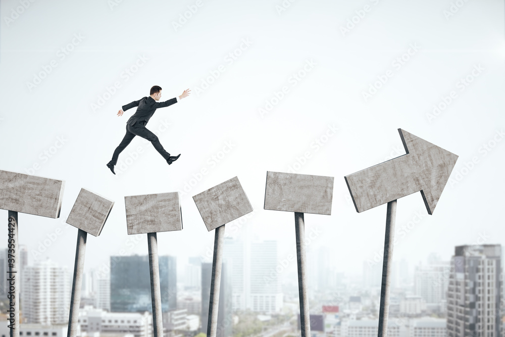 Businessman jumping on gray concrete arrow