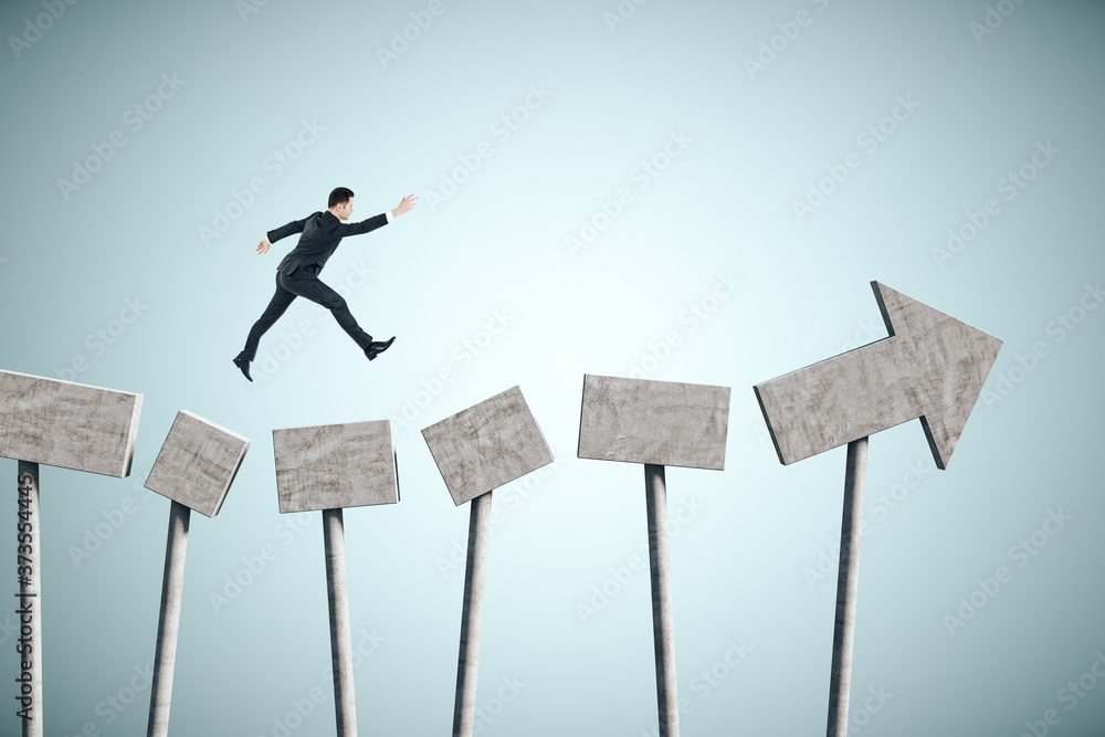 Businessman jumping on concrete arrow