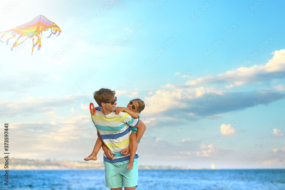 Man and his little daughter flying kite on sea beach at resort