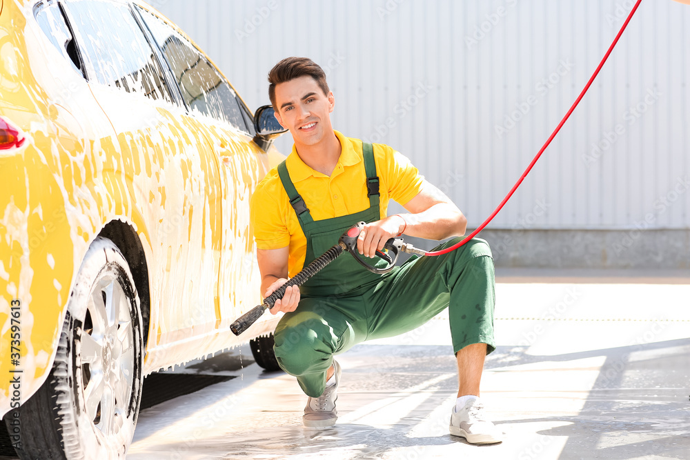 Worker of car wash cleaning modern automobile