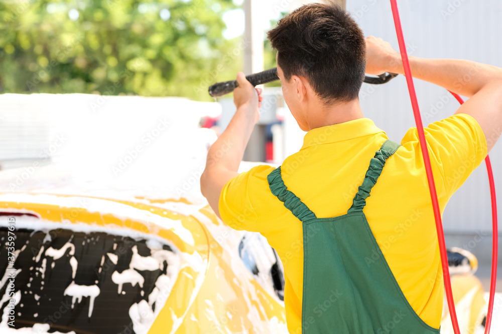 Worker of car wash cleaning modern automobile