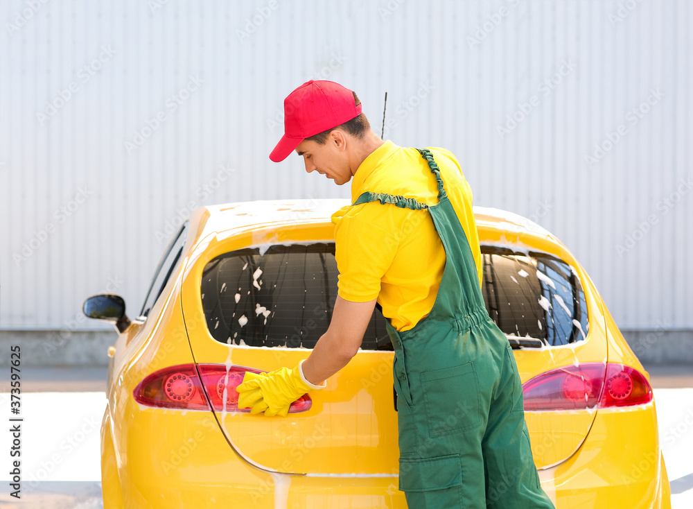 Worker of car wash cleaning modern automobile