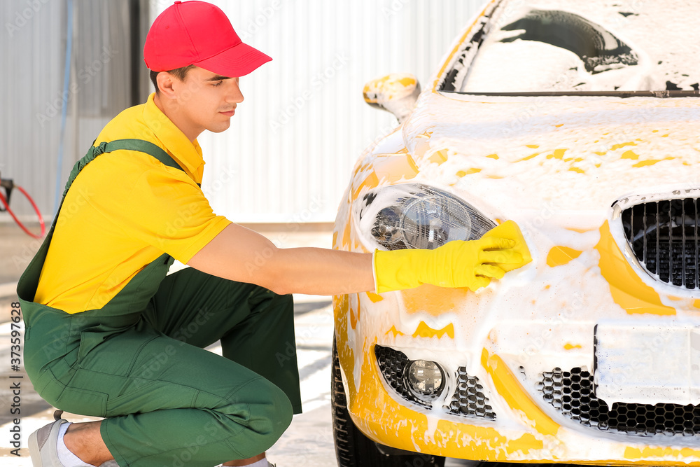 Worker of car wash cleaning modern automobile