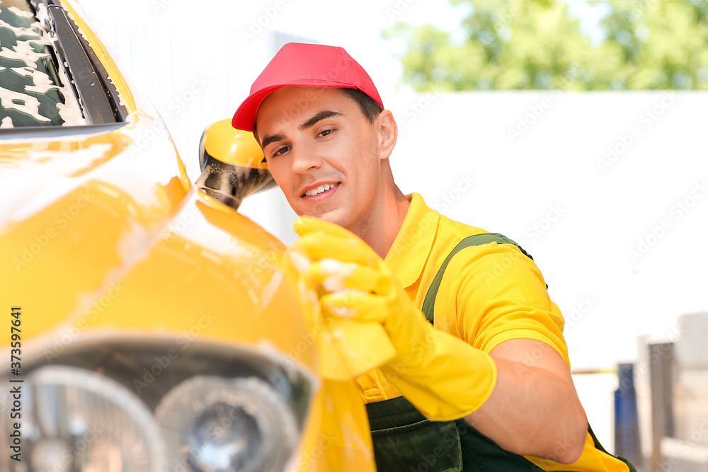 Worker of car wash cleaning modern automobile