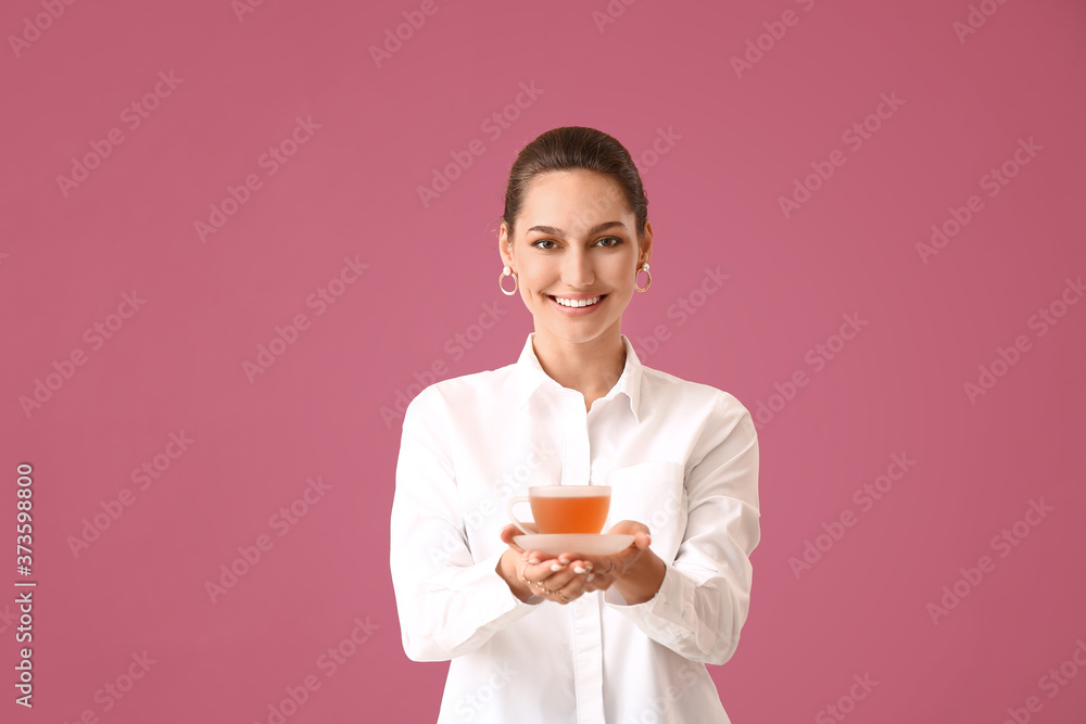 Beautiful young woman with cup of tea on color background