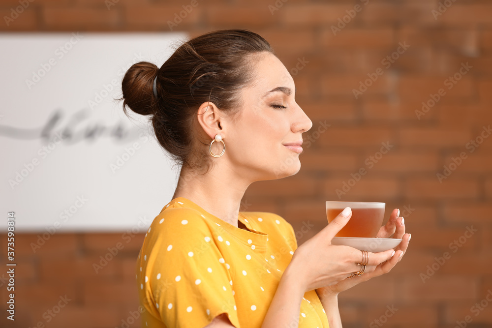 Beautiful young woman drinking tea at home