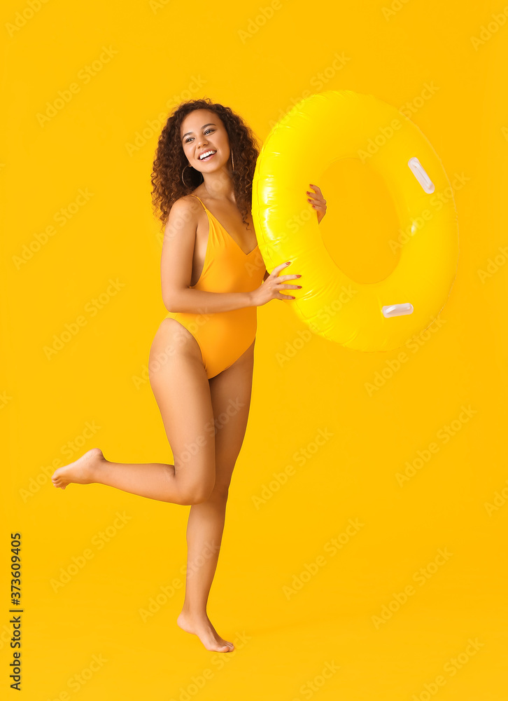 Beautiful young African-American woman with inflatable ring on color background