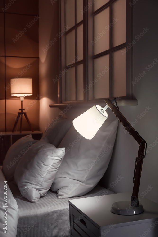 Interior of modern hotel room with glowing lamps at night