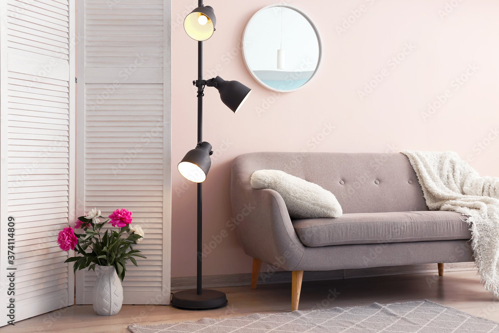 Stylish interior of room with sofa, lamp and mirror