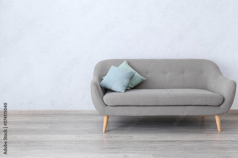 Stylish sofa near white wall