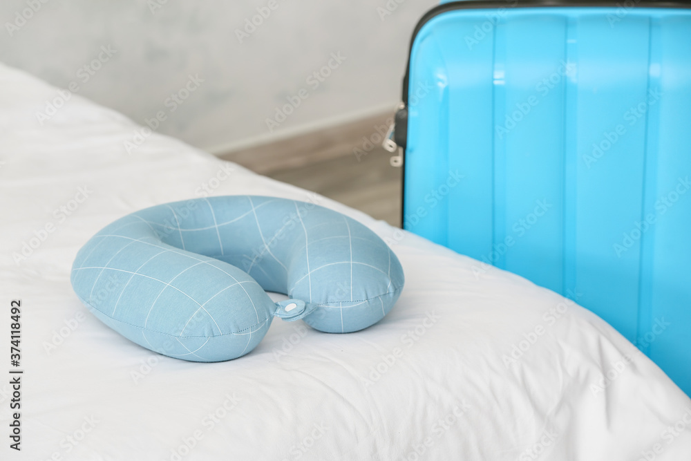 Travel pillow and suitcase in bedroom