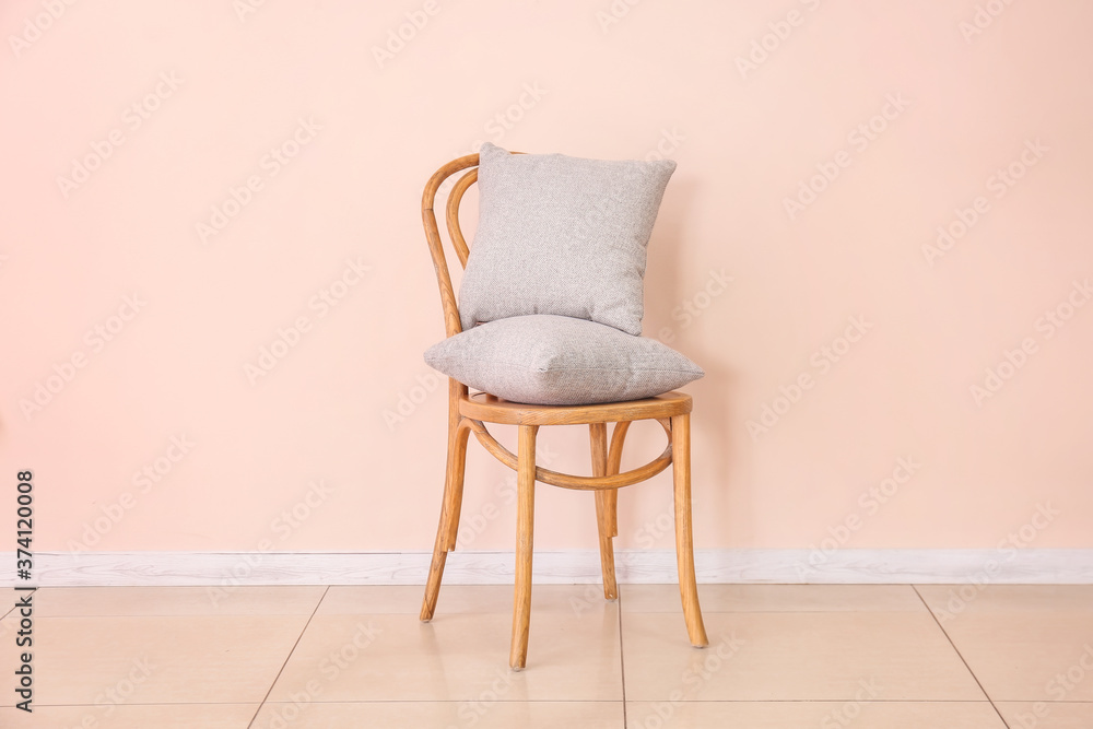 Chair with pillows near color wall in room