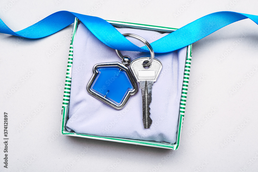 Gift box with key from house on light background