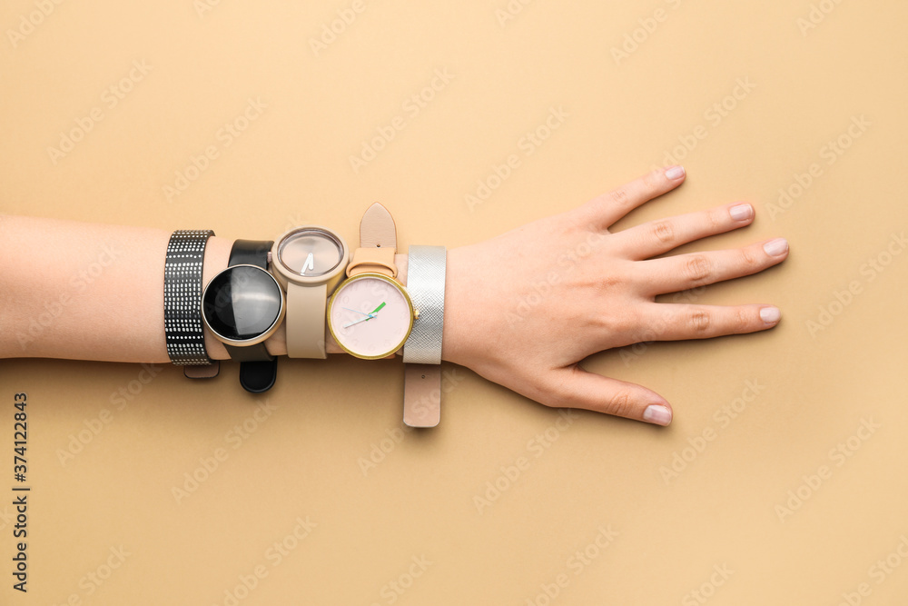 Female hand with stylish wrist watches on color background