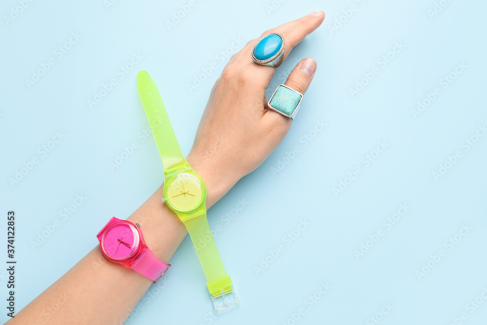 Female hand with stylish wrist watches on color background