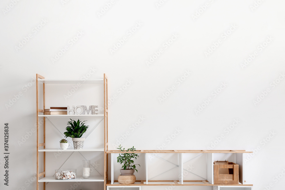 Stylish stand and rack with decor near light wall in room