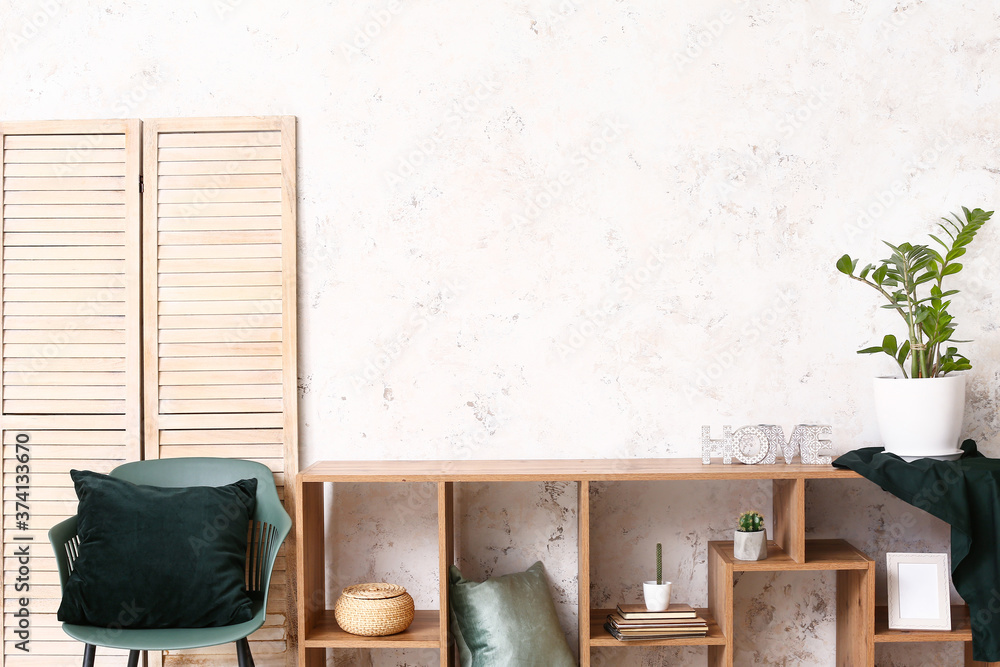 Wooden rack with decor near light wall in room