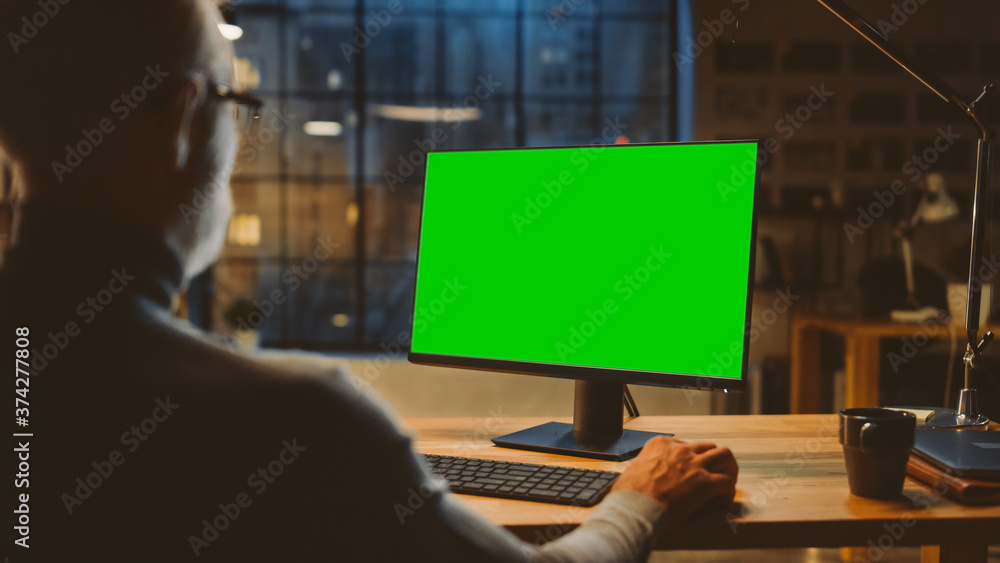 Over the Shoulder: Confident Middle Aged Man Sitting at His Desk Using Desktop Computer with Mock-up