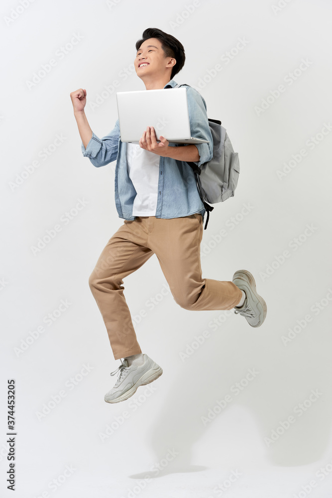 Full length body size of young Asian student man jumping in air using laptop with backapck isolated 