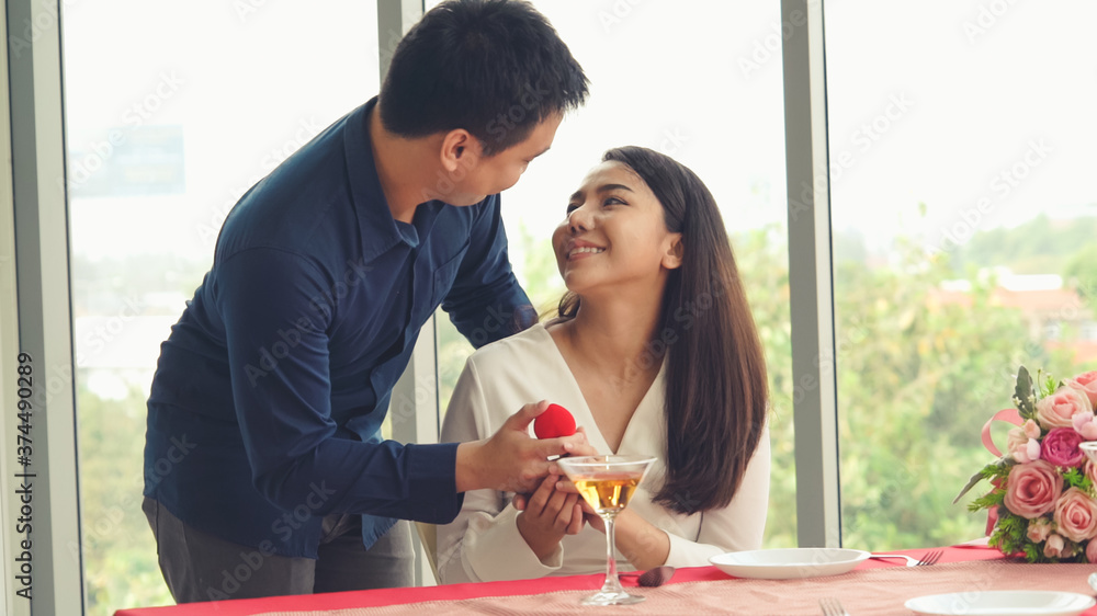 Romantic couple giving gift to lover at restaurant . Happy couple lifestyle .