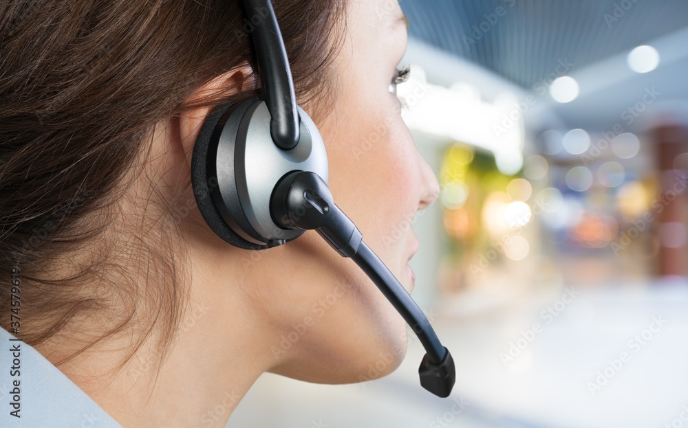 A young woman in headphones with a microphone working in a call center