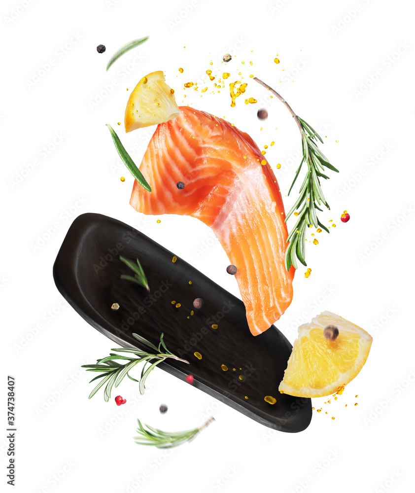 Slice of fresh salmon with spices and lemon in the air , isolated on a white background