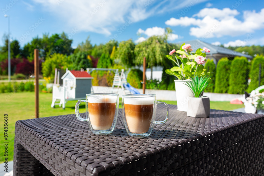 Two coffees on the table of sunny garden terrace