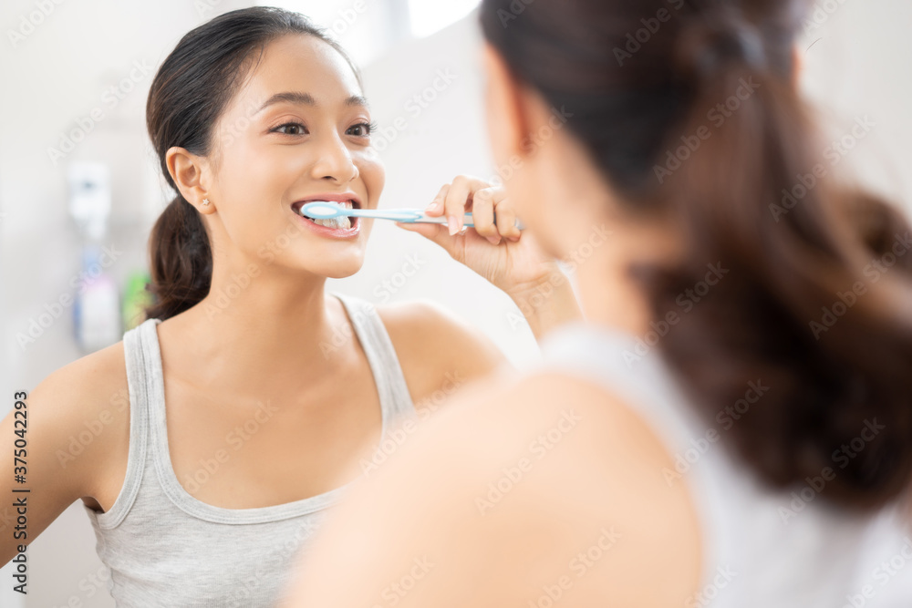 Beautiful female brushing teeth in the bathroom