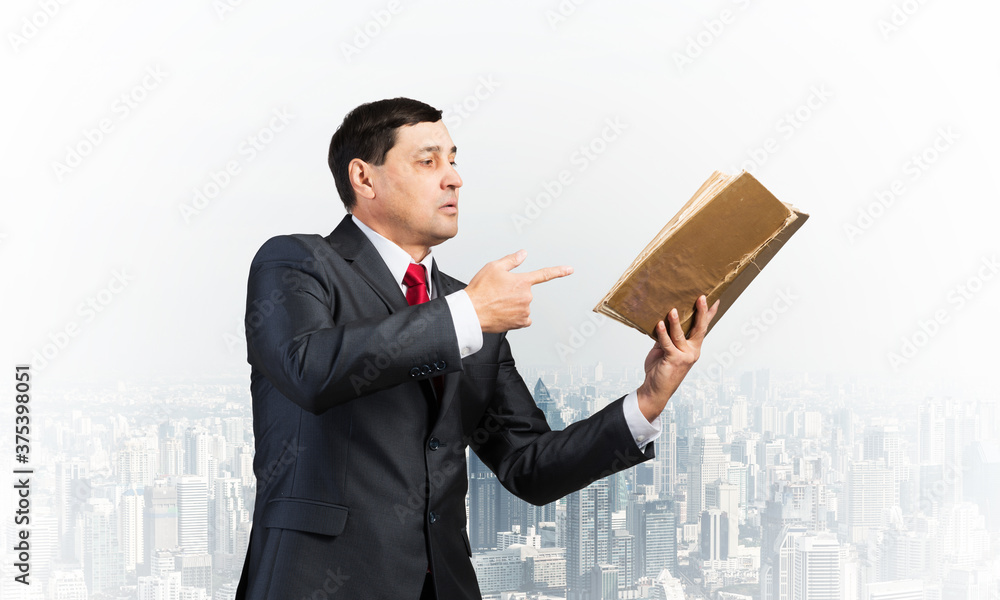 Senior businessman finger pointing into open book