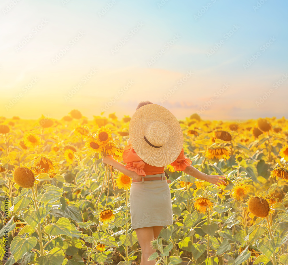 Beautiful young woman in sunflower field on sunny day