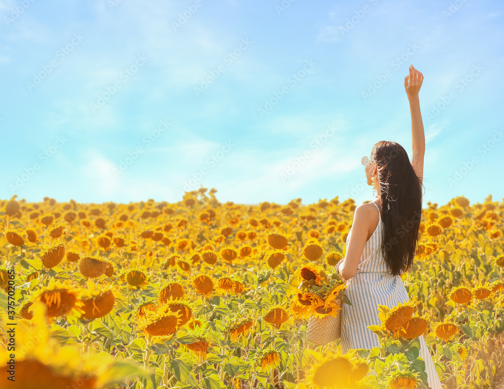 Beautiful young woman in sunflower field on sunny day