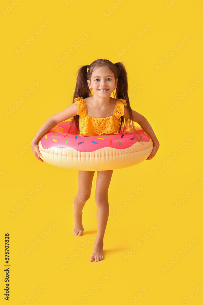 Little girl with swimming ring on color background